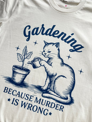 White tank top with blue graphic of a cat gardening and text 'Gardening Because Murder is Wrong'.
