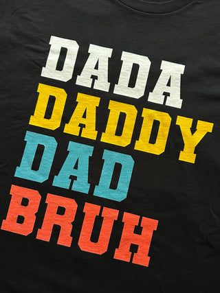 Black t-shirt with colorful text 'DADA DADDY DAD BRUH' on a plain background