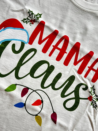 White t-shirt with 'Mama Claus' text and Christmas-themed graphics on a white background